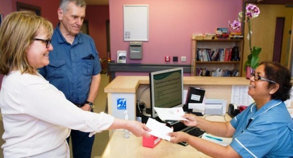 Couple at the day case reception desk with friendly receptionist