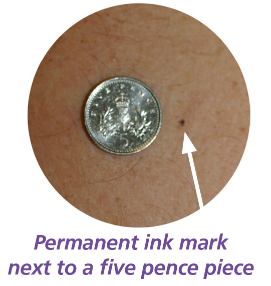 Photograph of a five pence piece next to  a permanent ink mark.
