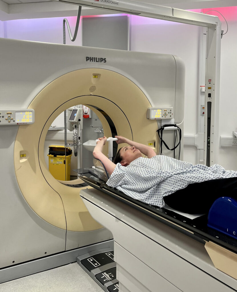 photo of patient with arms up on CT scanner couch