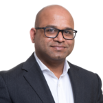 Dr Harish Bhandari headshot. Harish is wearing glasses and has a black suit jacket and a white shirt.