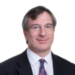 Professor Adam Balen headshot. Adam is wearing glasses and has a black suit jacket, white shirt and purple patterned tie.