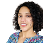 Dr Suhair Ibrahim headshot. Suhair has dark curly hair and she is wearing a blue, pink and yellow patterned blouse.