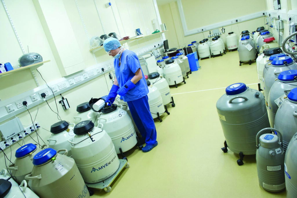 Photograph of scientist opening a tank where sperm are stored frozen.