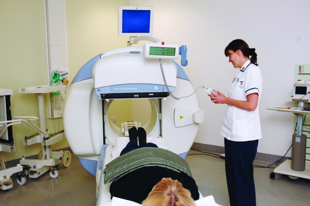 Photograph of a gamma camrea machine with patient and staff member