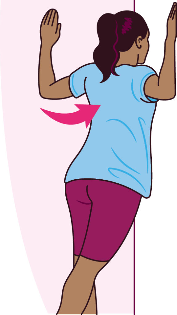 Illustration of Corner stretch exercise - a person stood facing the corner of a room, their hands are flat against each perpendicular wall at head height with the elbows bent. There is an arrow to indicate the person is pushing their body towards the corner.