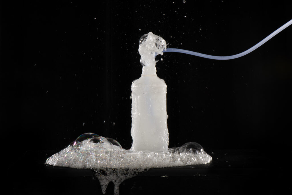 Photograph of a bottle with a tube going into it and bubbles coming out of the top