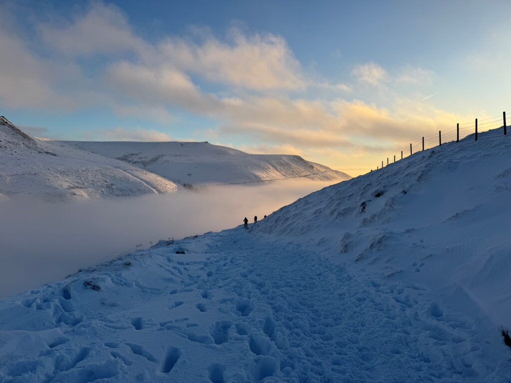 A snowy scene on the Pennine Way with blue skies and sunrise