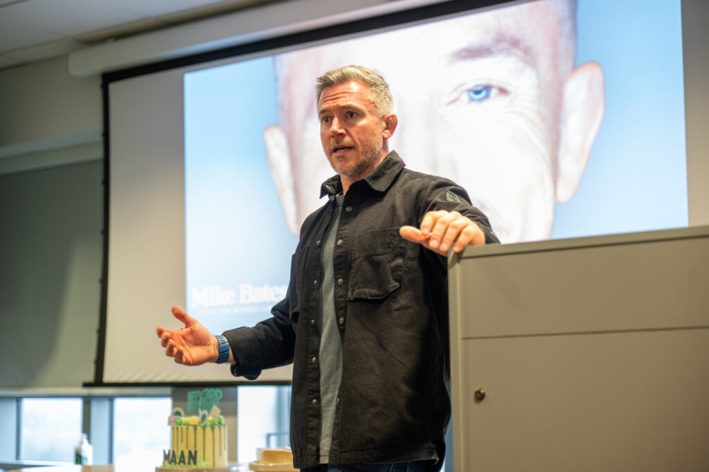 A man talking passionately in front of a projector screen.