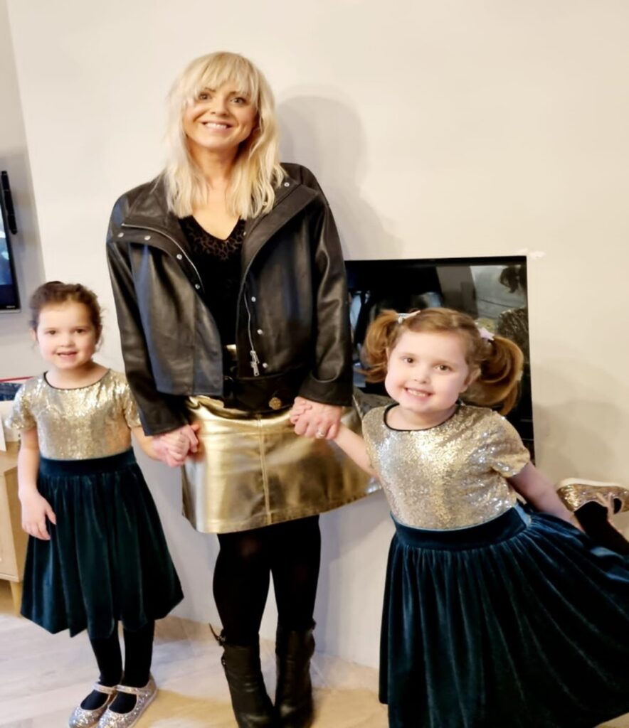 Aimee holding hands with her two young daughters