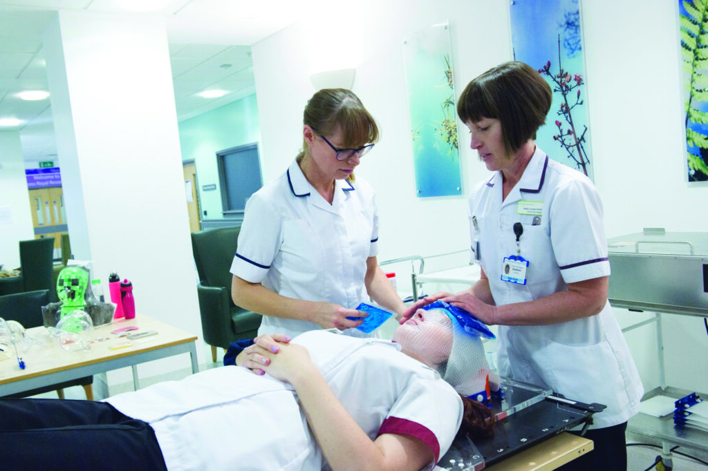 Photograph of mould room technicians working with a patient.

