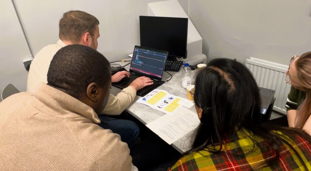 An image of attendees at the hackathon working on coding tasks.