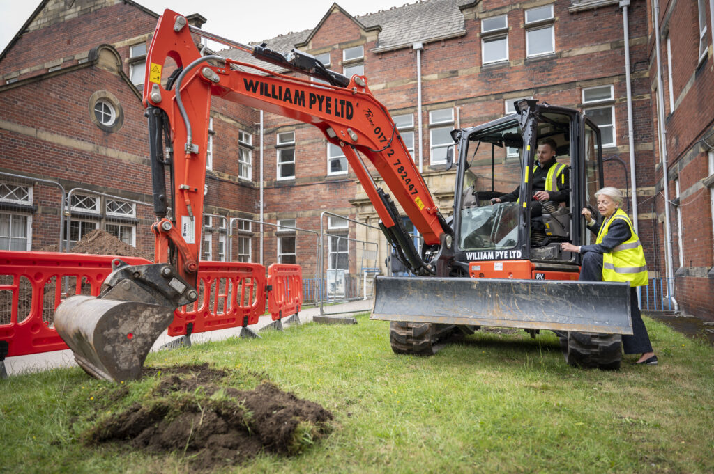linda pollard with digger and digger driver breaking ground for new garden development