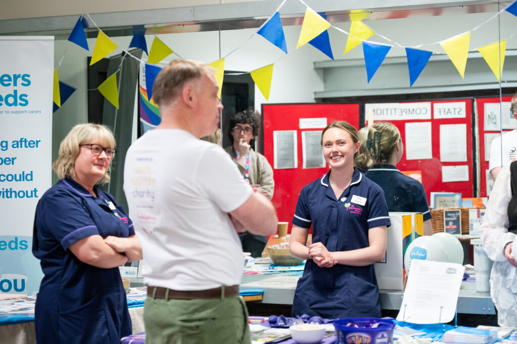 Three people talking at a stall