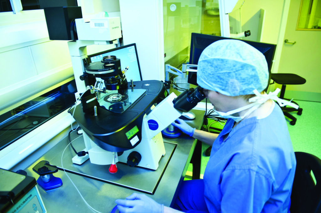 Photograph shows a scientist performing a sperm injection down a special microscope.