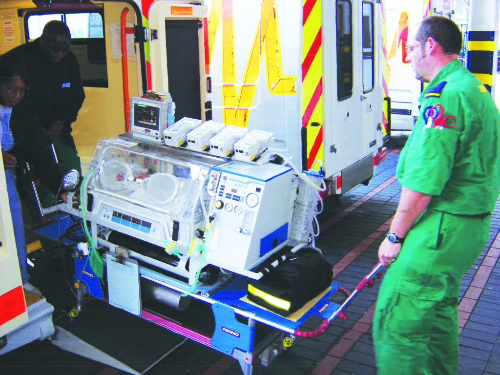 Photograph of a baby in an incubator being transferred into an ambulance.