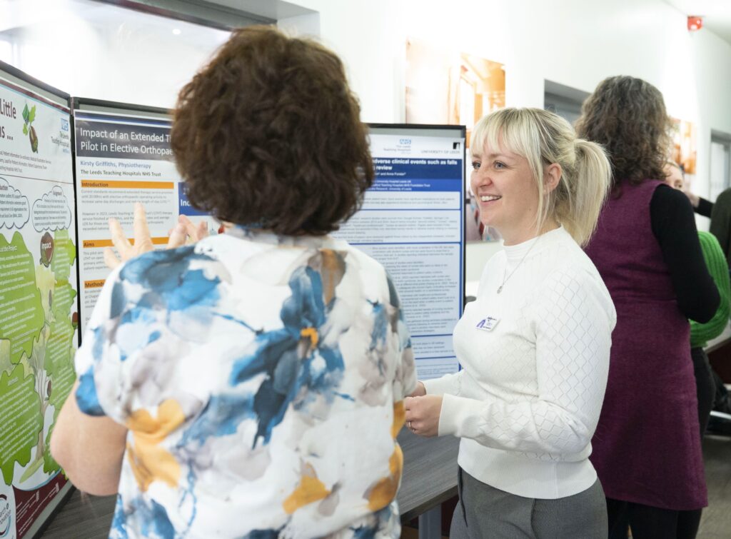 An image of two people discussing a research poster with the poster in the background.