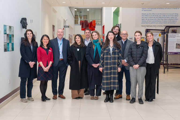A photo of the visitors standing in a hospital atrium with members of the Trust executive and senior Research & Innovation team members.