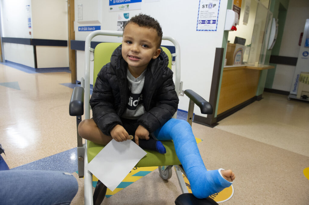 Photograph of a child in a wheelchair with a cast on their leg