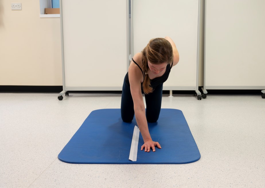 With hips extended, hop the hand over the tape (B) and back (C) to perform one repetition.