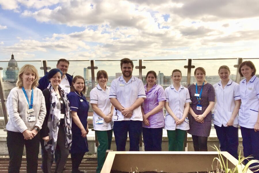Group of people dressed in various clinical uniforms gathered on hospital rooftop