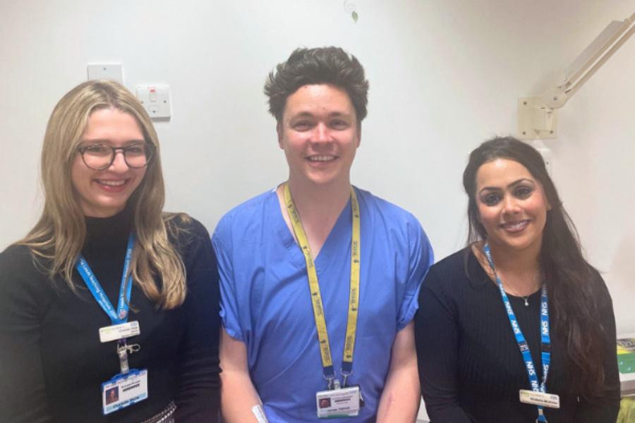 Two women in black and a man in blue scrubs