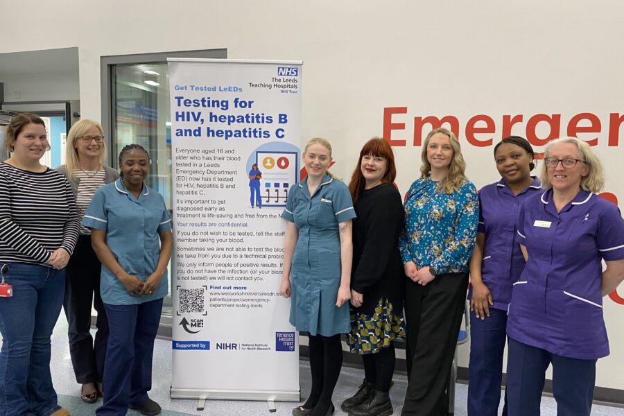 NHS staff standing in front of a banner in the emergency department