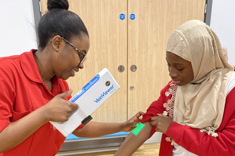 A phlebotomist from Leeds Teaching Hospitals uses a vein finder on a pupil from Shakespeare Primary School as part of their assembly.