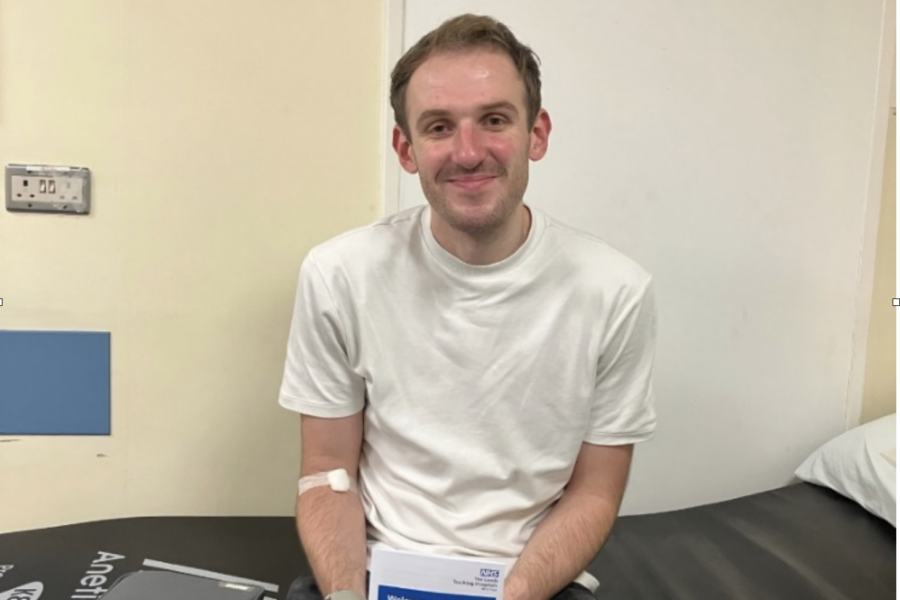 Picture of patient, Adam Etherington patient of the Trust's Virtal Ward. He is sat on a hospital bed holding the Virtual Ward information leaflet