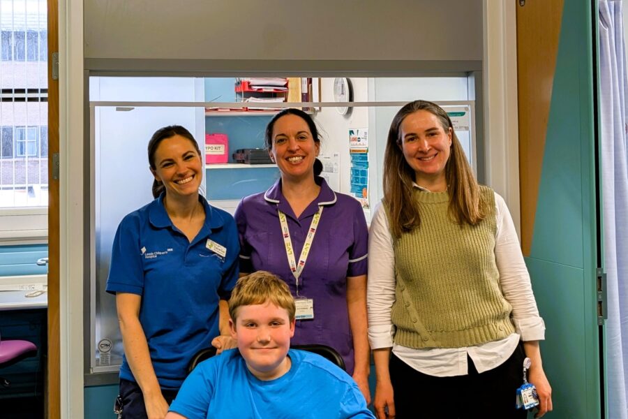 A photo of the patient Edward, with from left to right Claire Gee, physiotherapist, Donna Ellis, research nurse and Cristina Martos-Lozano, Consultant in Paediatric Neuromuscular Disorders.