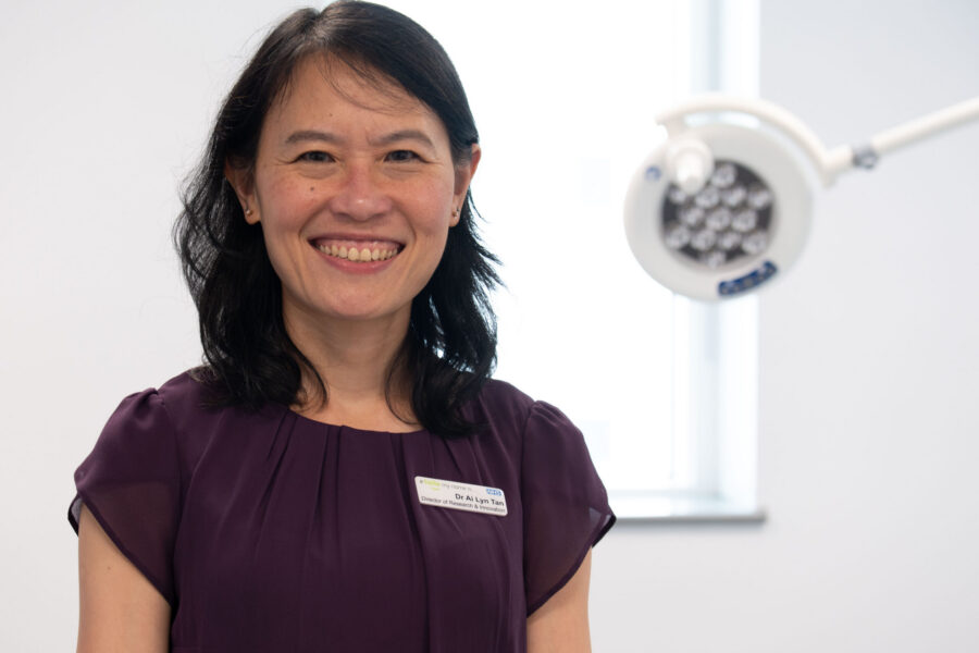 An image of Dr Ai Lyn Tan against a white background with a piece of medical lighting equipment visible in the background.
