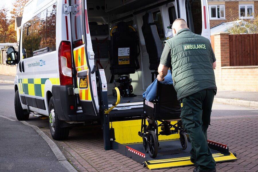 An image representing an Ambulance staff member helping a patient in a wheelchair into the back of the Ambulance. This is for promoting Patient Transportation across the Leeds Teaching Hospitals NHS Trust.