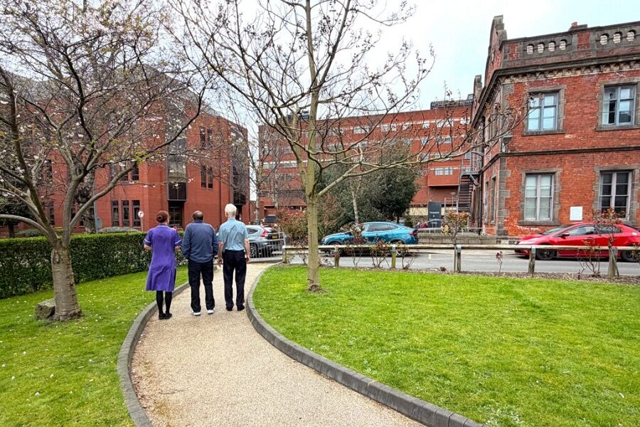 An image representing a staff nurse assisting assisting patients on a walking route across Bexley and Lincoln Wings.